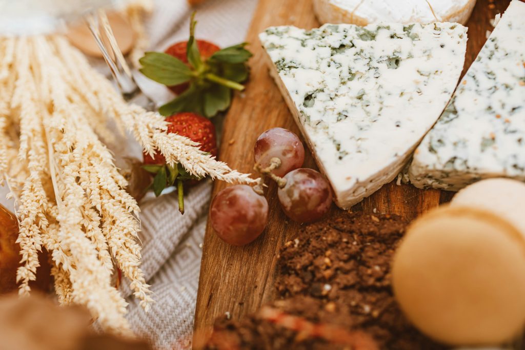 pexels-photo-6594992-6594992 A rustic food platter featuring blue cheese, grapes, and strawberries on a wooden board.